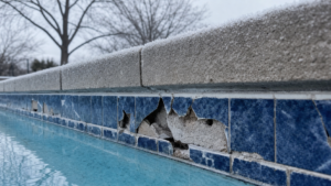 Freeze-thaw damage on swimming pool waterline tile and coping in a New England winter