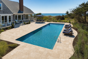 Newly installed travertine pool pavers surrounding a residential pool in Cape Cod, MA